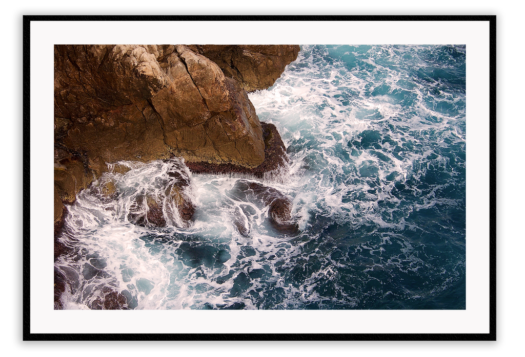 A natural wall art with a blue ocean rocks crashing waves on coastline white wash.