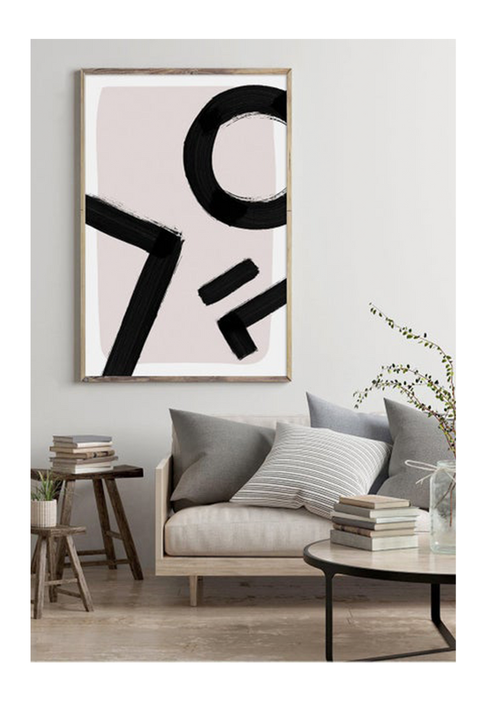 An abstract wall art with black ink brush lines on pink and white background.