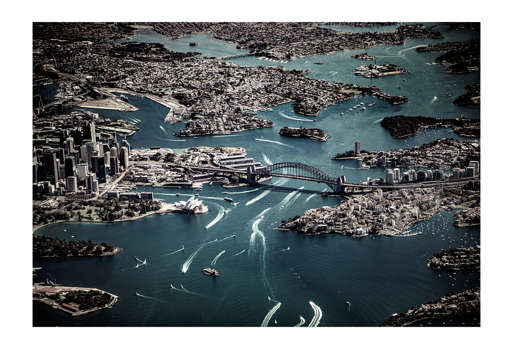 Birds eye view of sydney harbor with dark blue water and grey land  