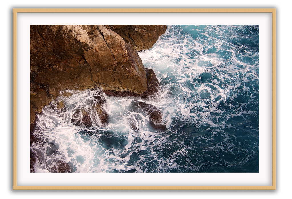 A natural wall art with a blue ocean rocks crashing waves on coastline white wash.