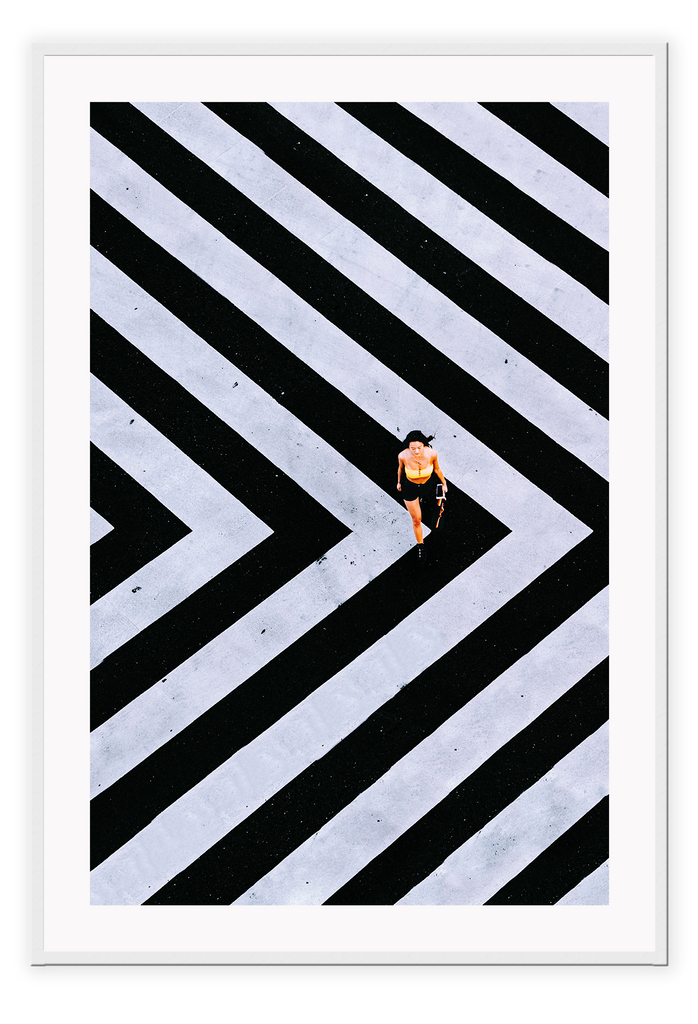 An urban wall art with an aerial view of a lady walking on black and white street crossing stripes