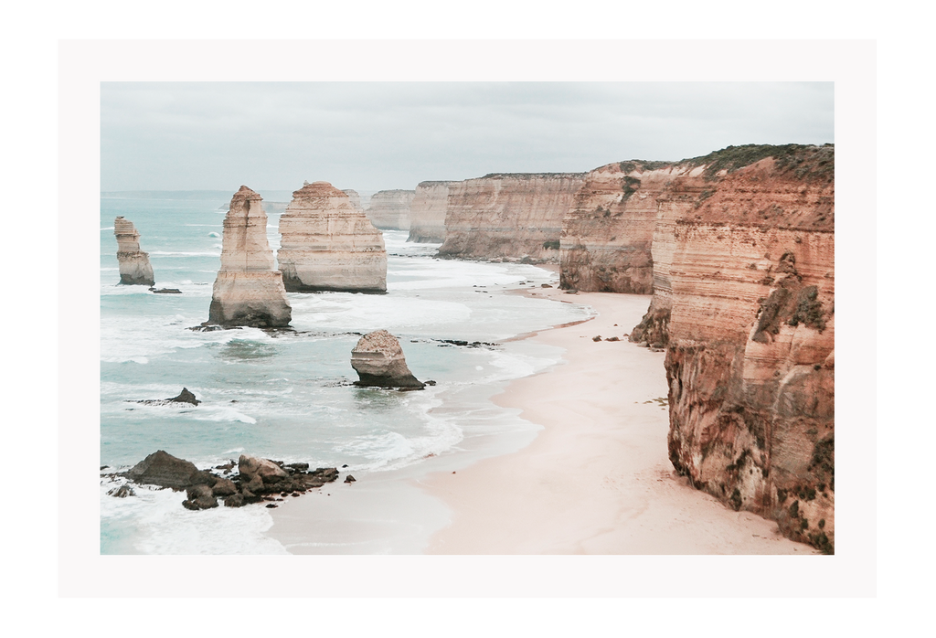 Landscape photography print showing the Twelve Apostles in Victoria, Australia with red rocks and cliffs sorrounded by sand and the ocean.